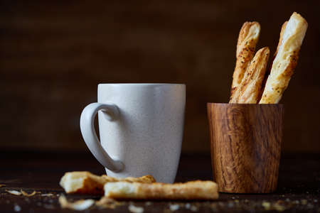 Coffee cup and breadsticks on an old wooden background, close-up, selective focus.の写真素材