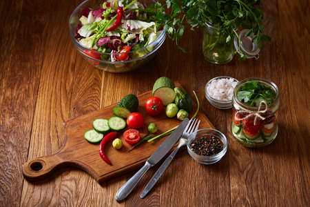Fresh red radish in wooden bowl among plates with vegetables, herbs and spicies, top view, selective focus.の写真素材