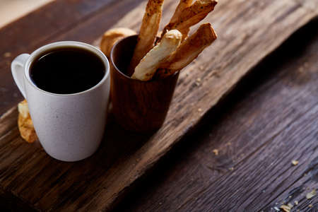 Coffee cup, breadsticks and croissants on an old wooden background, close-up, selective focus.
