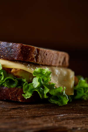 Tasty and fresh sandwiches on cutting board over a dark wooden background, close-up