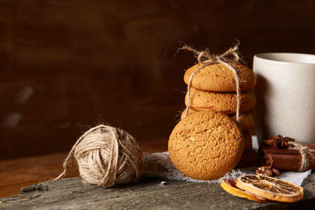 Traditional Christmas tea concept with a cup of hot tea, cookies and decorations on a wooden table,...
