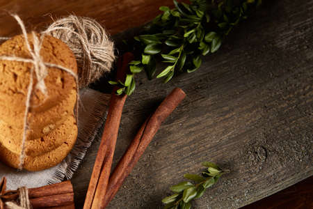 Christmas composition with pile of cookies stucked with ribbon, cinnamon sticks and dried oranges on...