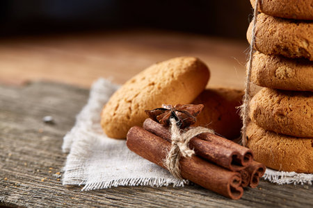 Christmas composition with pile of cookies stucked with ribbon, cinnamon sticks and dried oranges on...