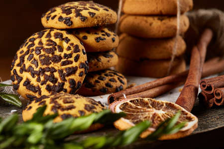 Christmas composition with pile of cookies stucked with ribbon, cinnamon sticks and dried oranges on...