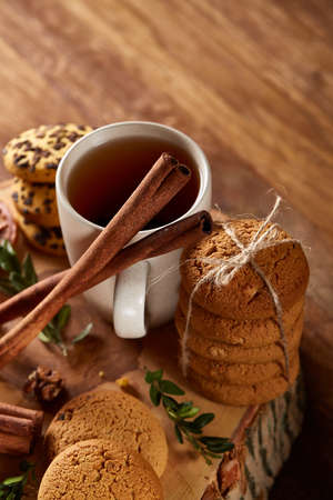 Christmas concept with a cup of hot tea, cookies and decorations on a log over wooden background, selective focusの写真素材