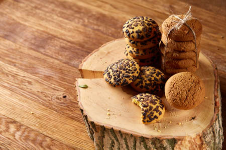 Sweet assortment of biscuits on a round wood log over rustic wooden background, close-up, selective...