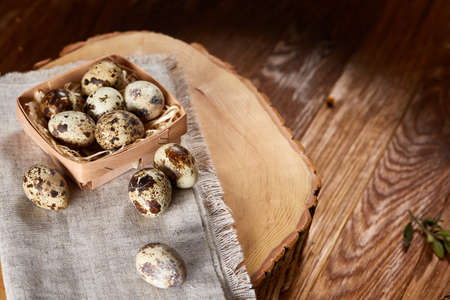 Composition of eggs quail box, eggs on a homespun napkin on a log over wooden background, top viewの写真素材