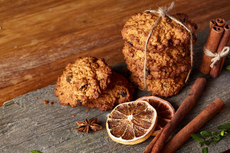 Christmas composition with chocolate biscuits, cinnamon and dried oranges on wooden background, close-up.の写真素材