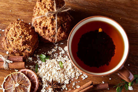 Christmas teatime with oatmeal, chocolate biscuits, and spices, on wooden background, close-up, selective focus.の写真素材