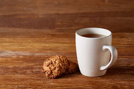 White porcelain mug of tea and sweet cookies on wooden background, top view, selective focusの写真素材