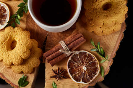 Christmas concept with a white cup of hot tea, cookies and decorations on a log over wooden background, selective focusの写真素材