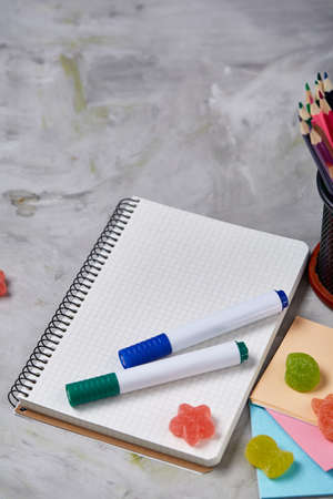 A notebook, two markers and assortment of jelly beans on a white background, copy space for text,...
