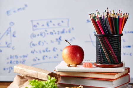 Back to School concept, school supplies, biscuits, packed lunch and lunchbox over white chalkboard,...