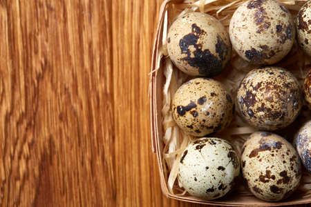 Quail eggs in a box on a rustic wooden background, top view, selective focus.