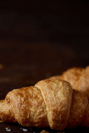 Tasty buttery croissants on an old wooden table, close-up, selective focus, shallow depth of field....