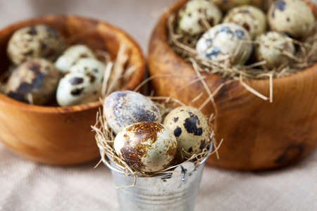 Wooden bowl with quail eggs, eggs on a homespun napkin on grey background, close-up, selective...