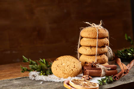 Christmas composition with pile of cookies stucked with ribbon, cinnamon sticks and dried oranges on...