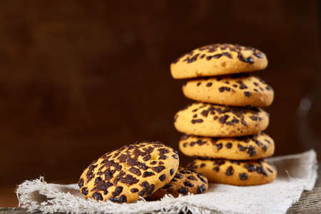Stacked chocolate chip cookies on white homespun napkin in country style on wooden table. Chocolate...