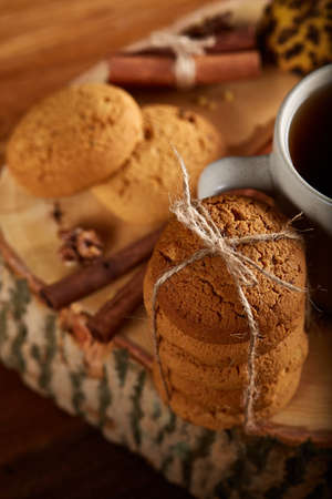 Christmas concept with a cup of hot tea, a large set of cookies on a homespun napkin, cinnamon...