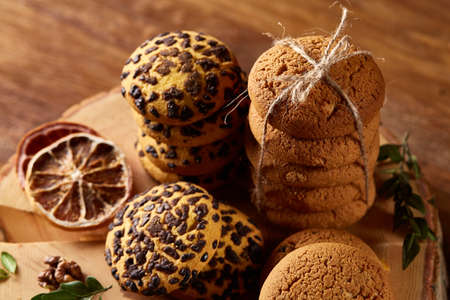 Sweet assortment of biscuits on a round wood log over rustic wooden background, close-up, selective...