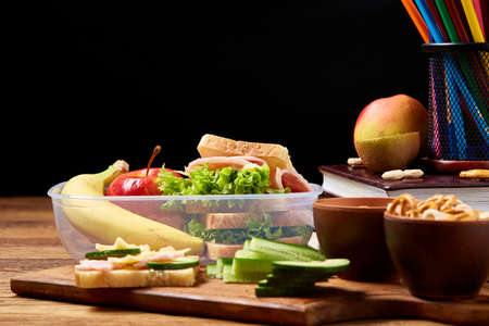 Healthy eating kid's menu on school lunch background, shallow depth of field, close-up. Different crunchies in ceramic bowls in front of textbooks on wooden desk. Nutritious snack while studyingHealthy food concept.の写真素材