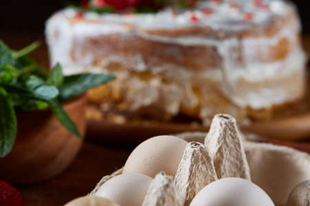 Raw ingredients for cooking strawberry pie or cake on wooden table: eggs, mint and strawberry,...