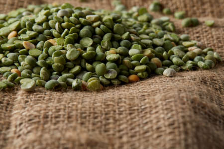 Pile of green peas on burlap tablecloth, close-up, top view, selective focus, shallow depth of...