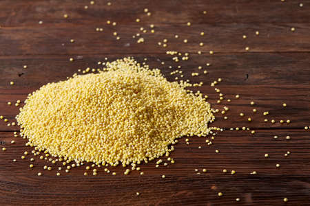 Pile of natural organic millet on rustic wooden background, top view, close-up, selective focus. Some copy space for your text. Lentils background. Lentils pattern. Nutritious organic lentils for healthy food. Healthy eating and dieting.の写真素材
