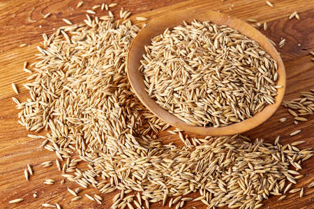 Oat groats or oat spike in wooden plate on old wooden background, copy space, top view, selective...