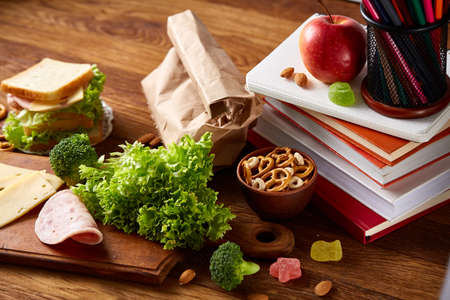 Concept of school lunch break with healthy lunch box full of sandwiches, fruits and vegetables and...