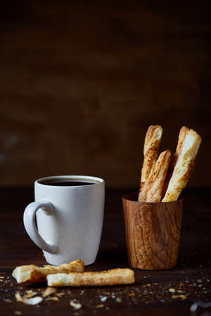 White porcelain coffee cup and freshly baked breadsticks on an old wooden background, close-up, selective focus. Light breakfast concept. Yummy sweetbread. Rural still life. Food concept.の写真素材