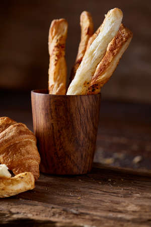 Puff pastries on piece of board over dark wooden table, close-up, selective focus, backlight....