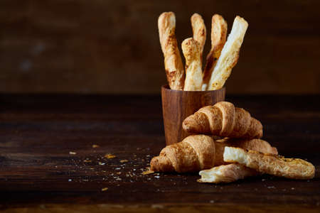 Puff pastries on piece of board over dark wooden table, close-up, selective focus, backlight....