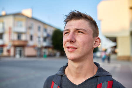 A young happy guy with problem skin having fun while walking around the summer city.の写真素材