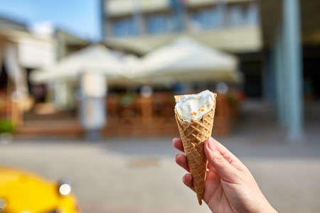 A first person view, a person walking along the road, holding ice cream in her hands and eating it...