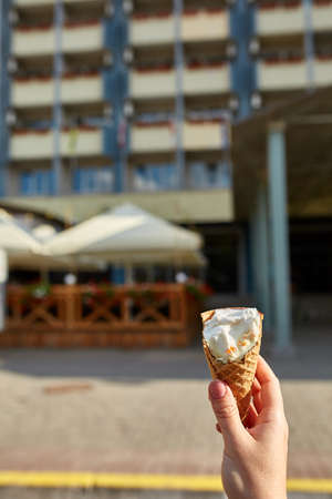 A first person view, a person walking along the road, holding ice cream in her hands and eating it...