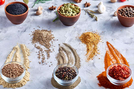 Different bowls with spices arranged in rows on white textured background, top view, selective focus. Some clipping path between them. Glass bowls with chilly, peppercorns, coriander opposite to clay bowls with cardamon and other spicies.の写真素材