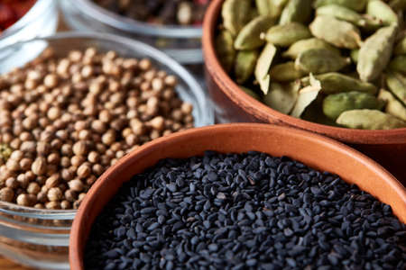 Bowls with different types of spicy on wooden table, top view, close-up, selective focus. Pimento, black sesam, coriander, cardamon, on rustic wooden background. Aromatic flavouring. Healthy eating and dieting concept.の写真素材