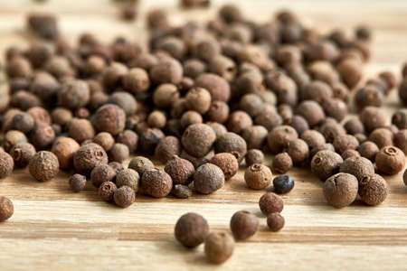Close-up pile of pimento or allspice on light wooden background, top view, macro, shallow depth of...