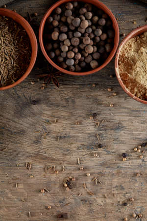 Spices in ceramic bowls on the top of wooden barrel, close-up, selective focus, vertical. Aromatic ingredients and natural food additives. Healthy eating concept. Food background. Exotic flavouring. Natural seasoning. Gourmet allspice diversity.の写真素材
