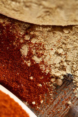 Top view of a wooden spoons full of paprica and black pepper on wooden barrel background, selective...