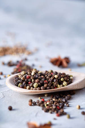 Peppercorns in wooden spoon with clipping path on white textured background, close-up, selective...