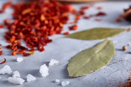 Red hot chillies pepper flakes in wooden spoon on white textured background, top view, close-up,...