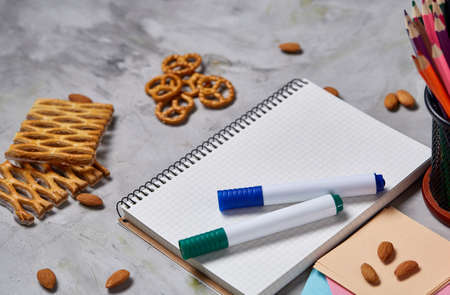 A notebook, two markers and assortment of jelly beans on a white textured background, copy space for...
