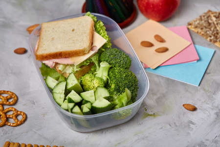 School or picnic lunch box with sandwich and various colorful vegetables and fruits on wooden background, close up. Healthy eating habits concept. Dietary composition on rustic wooden background. Preparation for having a snack.の写真素材
