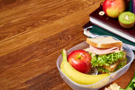 School or picnic lunch box with sandwich and various colorful vegetables and fruits on wooden background, close up. Healthy eating habits concept. Dietary composition on rustic wooden background. Preparation for having a snack.の写真素材