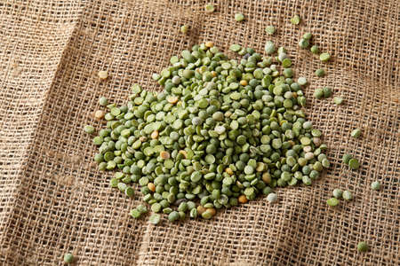 Pile of green peas on burlap tablecloth, close-up, top view, selective focus, shallow depth of...