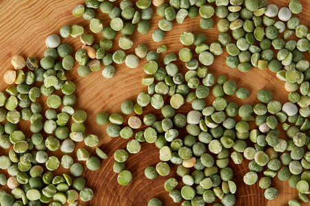 Pile of green peas on a wooden log, close-up, top view, selective focus. Some copy space for your inscription. Studio shot. Macro. Nutritious organic protein. Healthy food concept. Healthy eating, dieting.の写真素材