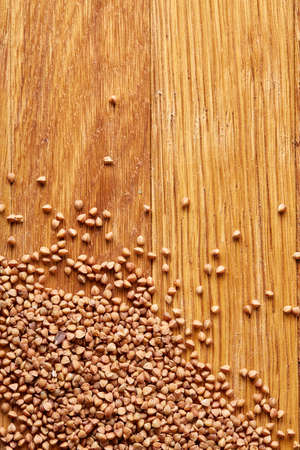Buckwheat groats on wooden background, top view, close-up, selective focus. Some copy space for your text. Premium cereal for healthy eating or dieting. Healthy food concept.の写真素材