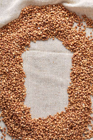 Buckwheat groats on burlap background, top view, close-up, selective focus, shallow depth of field, vertical. Buckwheat background. Useful natural cereal. Organic garnish. Premium cereal for healthy eating or dieting. Healthy food concept.の写真素材